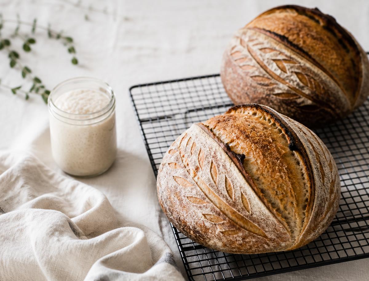 Freshly baked artisan sourdough loaves with golden crackly crusts on a flour-dusted surface